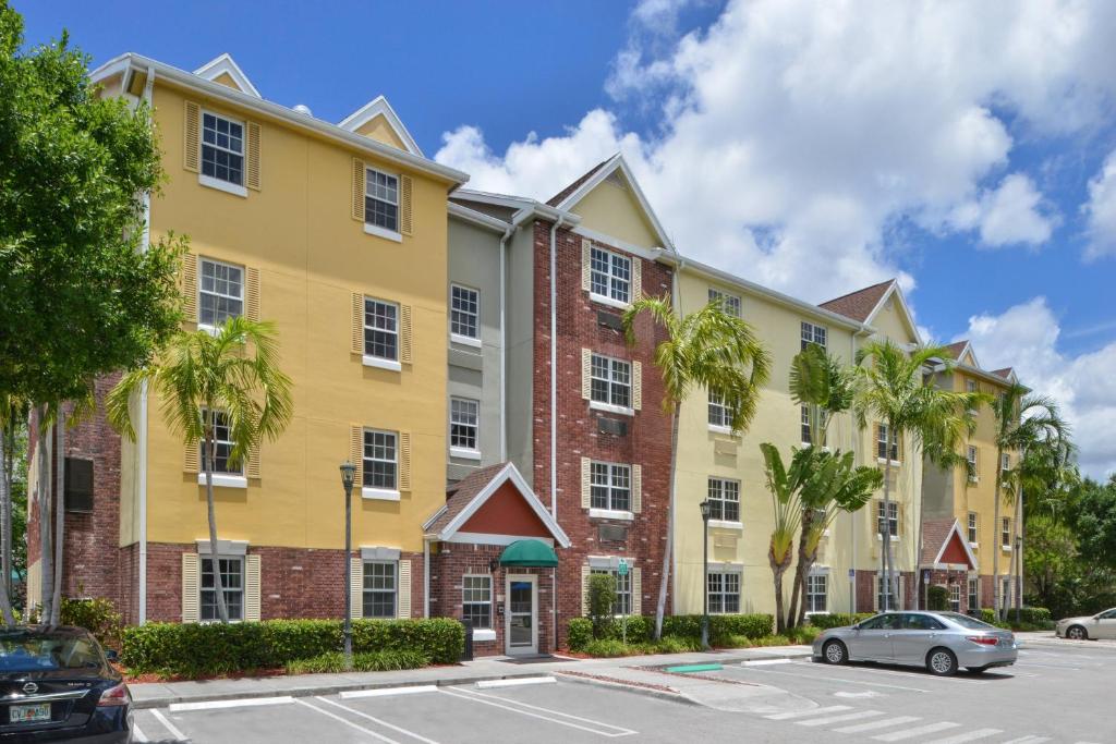 迈阿密TownePlace Suites Miami West Doral Area的停车场内棕榈树的大型黄色建筑