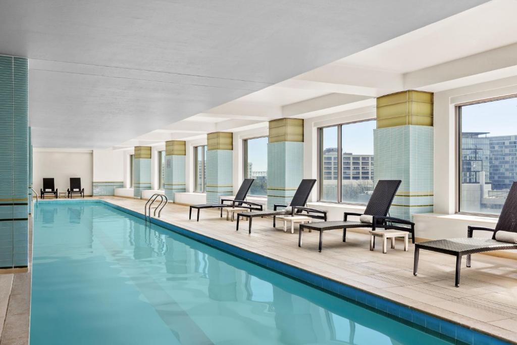 波士顿水岸万丽酒店的一座带躺椅和桌子的游泳池位于大楼旁
