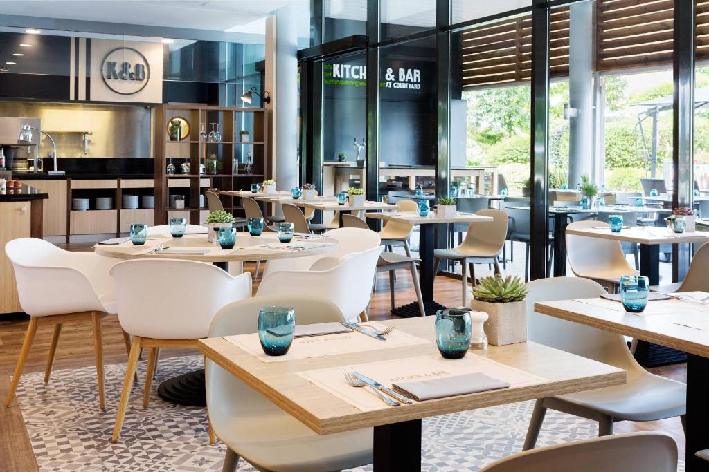 图卢兹万豪图卢兹机场度假酒店的配有木桌和白色椅子的餐厅