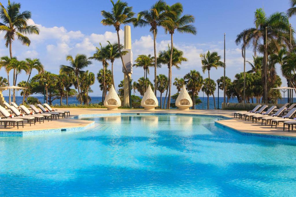 圣多明各复兴圣多明各雅拉瓜酒店&俱乐部的一个带椅子的游泳池,棕榈树