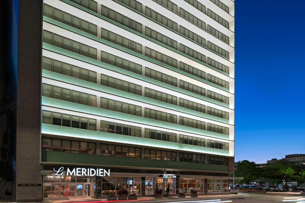 休斯顿Le Meridien Houston Downtown的一座高大的建筑,旁边有一个标志