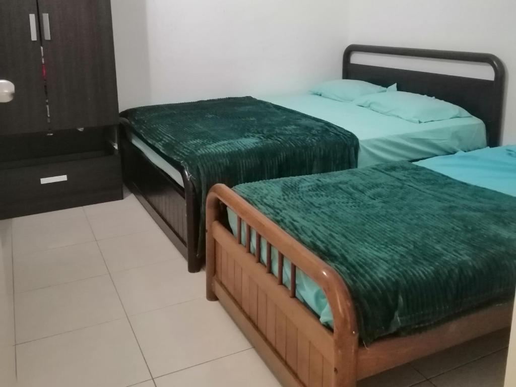 哥打巴鲁Sis Homestay Wakaf Che Yeh, Kota Bharu的客房内的两张床和绿色床单