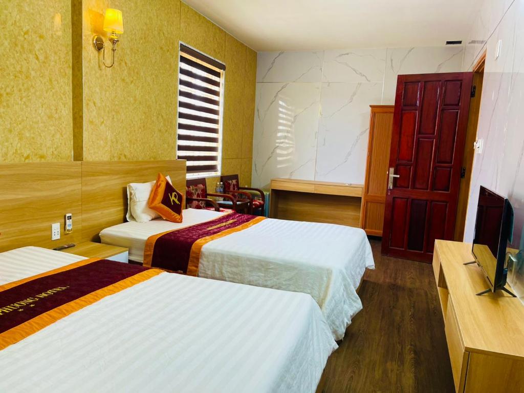 Quảng TrịKhách sạn Khánh Phương的酒店客房设有两张床和一台平面电视。