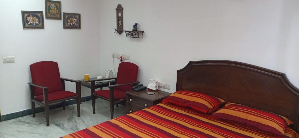 诺伊达Blessings Noida Home stay的一间卧室配有一张床、两把椅子和一张桌子