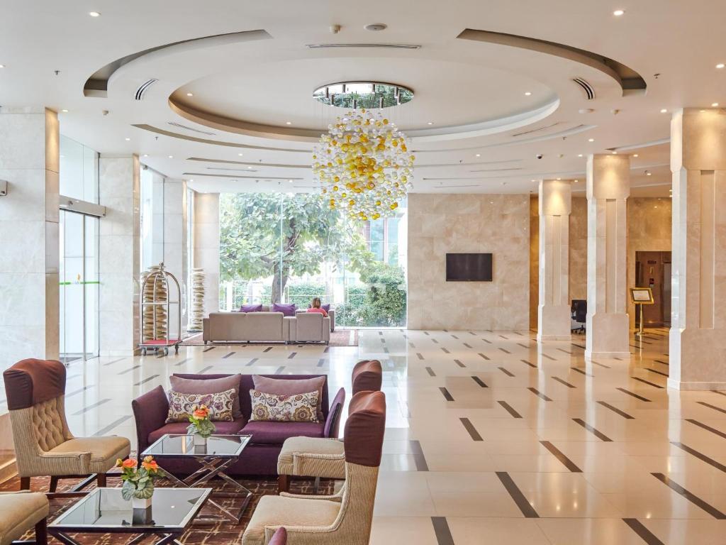 曼谷枫叶酒店的大堂设有紫色的沙发、椅子和吊灯