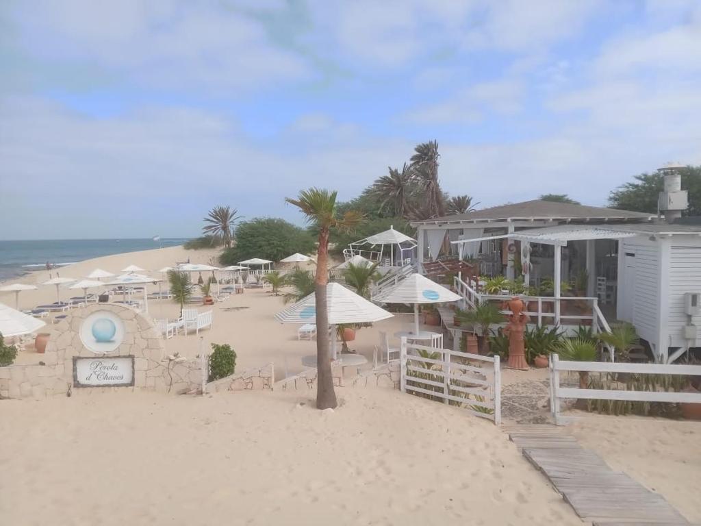 萨尔雷Útulný apartmán na Praia de Chaves, Boa Vista的一个带椅子和遮阳伞的海滩和一座建筑