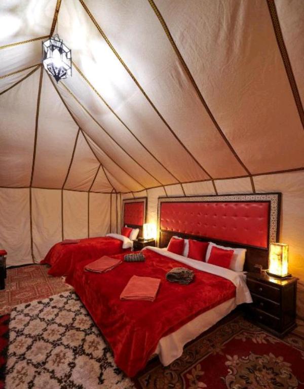 梅尔祖卡Luxury Local Camp的一间帐篷内带红色床的卧室