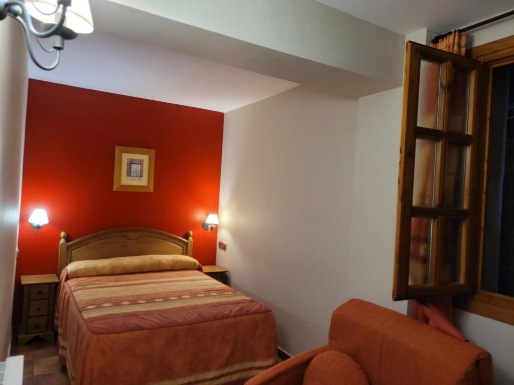 布罗托Apartamentos Casa Español的卧室设有红色的墙壁、一张床和椅子