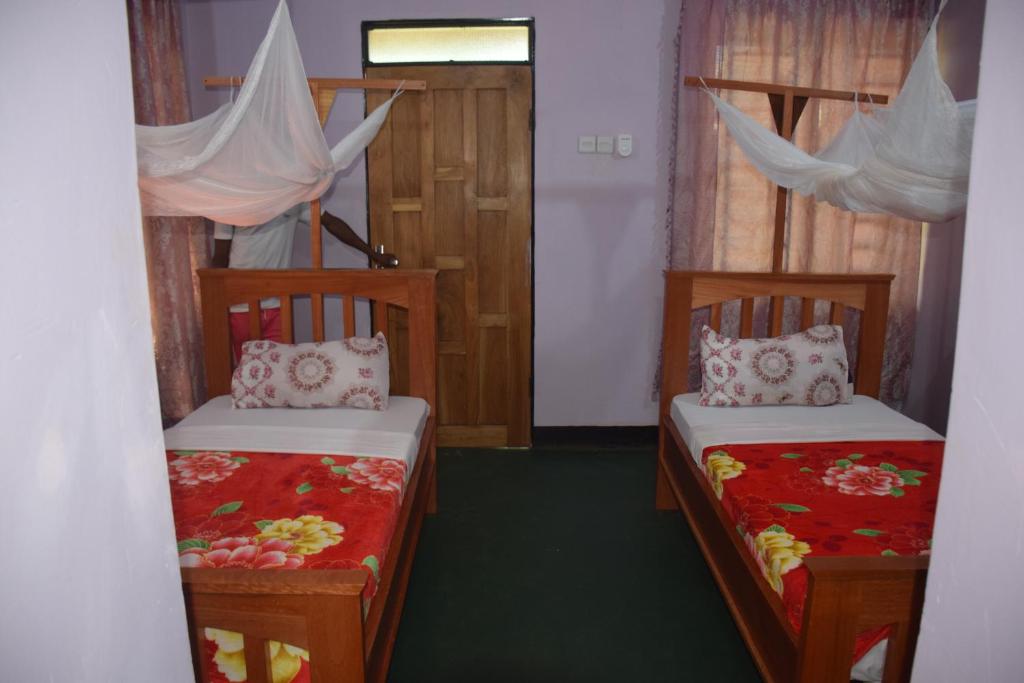 莫希Kili View Lodge的一间设有两张床的客房和一个带窗帘的门