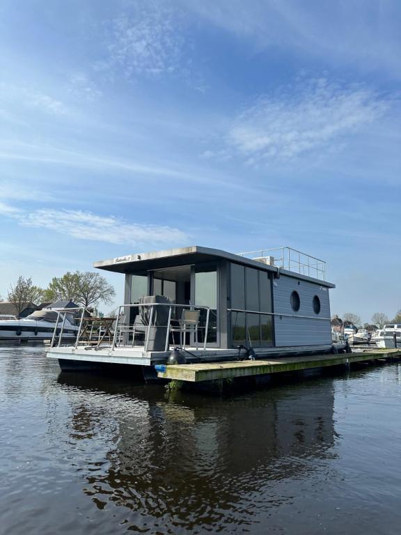 Belt-SchutslootStoere HOUSEBOAT op toplocatie!的船屋船坐在水面上的码头上