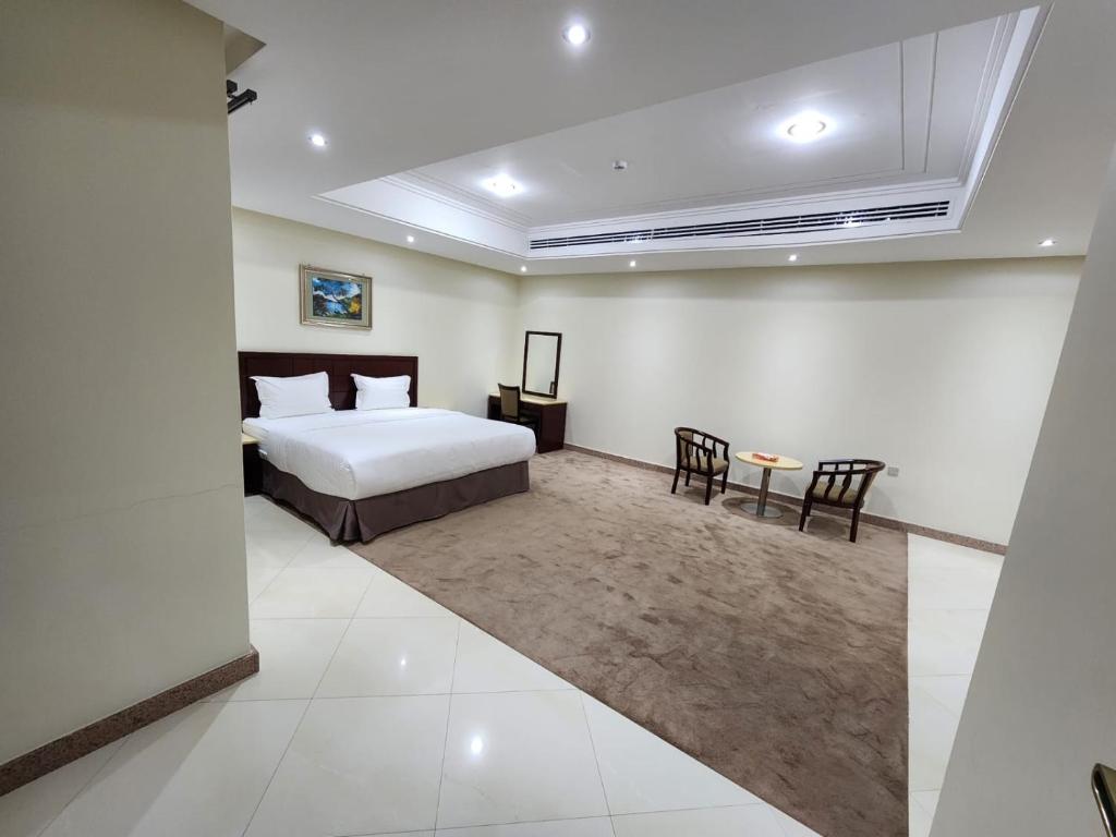 达曼S Maskan Hotel的卧室配有一张床和一张桌子及椅子