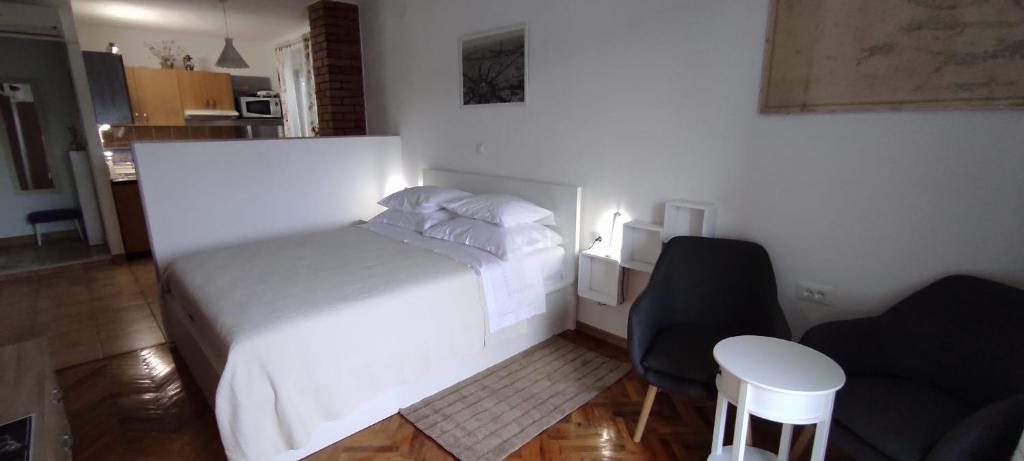 苏曼婷Studio Apartment Riva的卧室配有白色的床和椅子