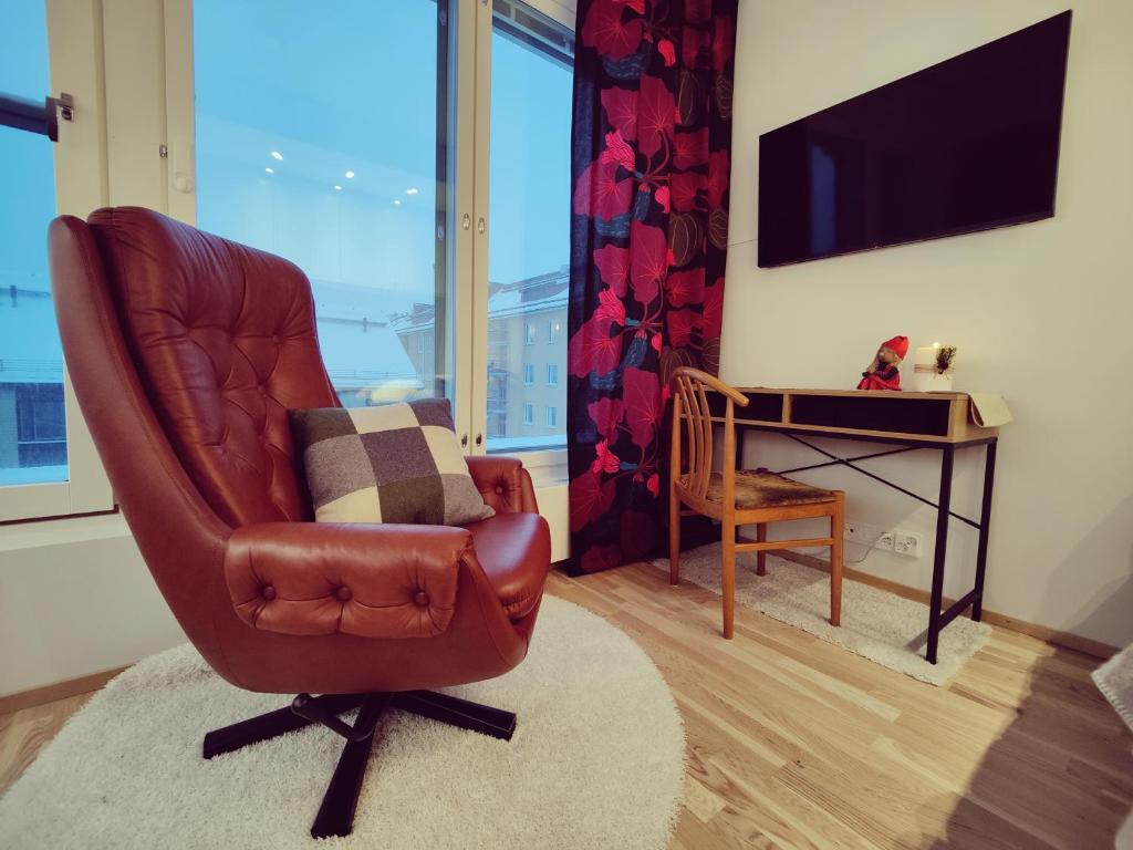 坦佩雷Ydinkeskustassa, uusi yksiö+ autohallipaikka的客厅配有棕色真皮座椅和书桌
