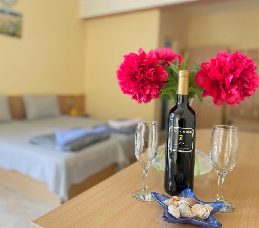 巴尔奇克Family Hotel Morska Zvezda的一瓶葡萄酒和两杯带鲜花的桌子