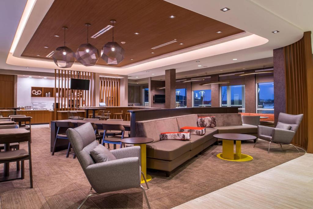 FriendshipSpringHill Suites by Marriott Greensboro Airport的酒店大堂设有沙发和桌子,还有一间酒吧