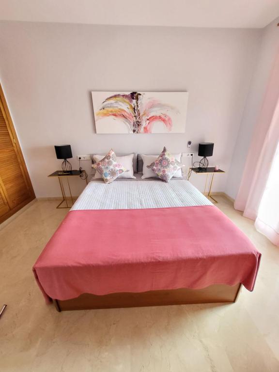 多列毛利诺斯APARTAMENTO PLAYA LA VIÑA P的一间卧室配有一张带粉色毯子的大床