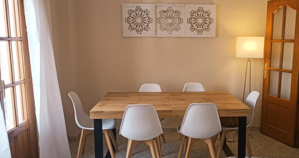 隆达Apartamento Dama Centro的一间带木桌和白色椅子的用餐室