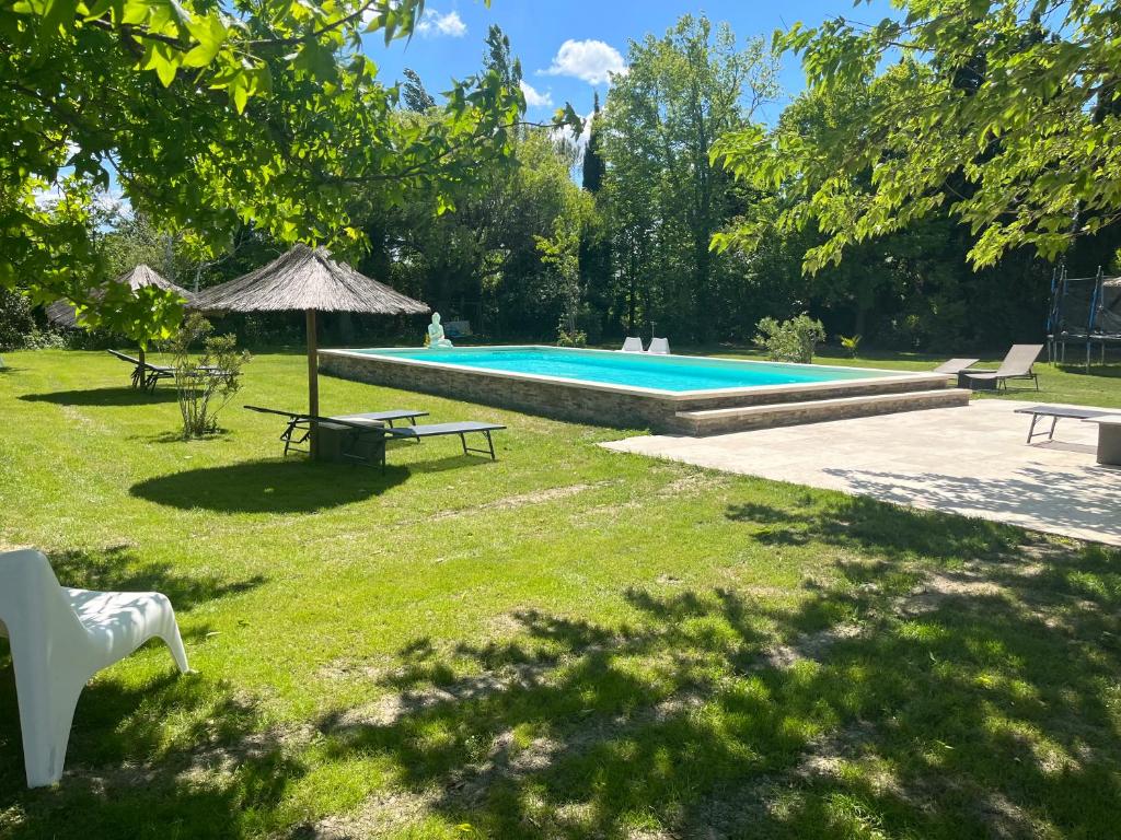 BédarridesLe jardin de Jade的庭院设有带野餐桌和遮阳伞的游泳池