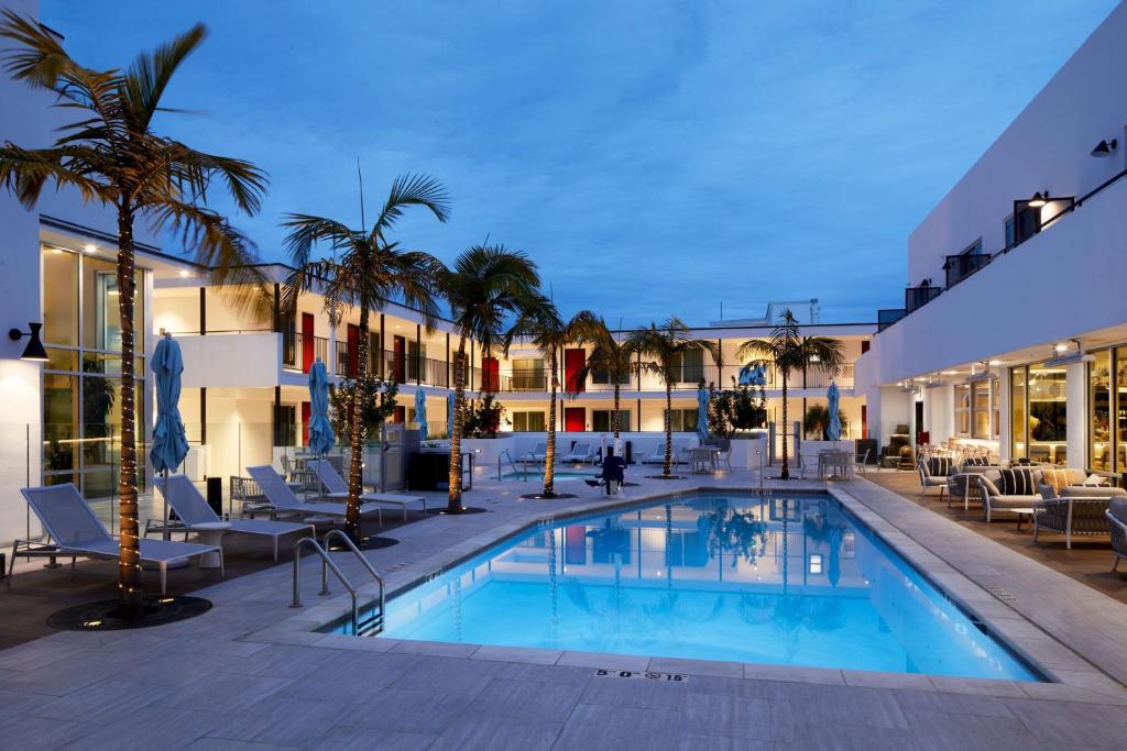 圣巴巴拉圣巴巴拉市中心拉金塔旅馆的一座游泳池,里面摆放着椅子和棕榈树