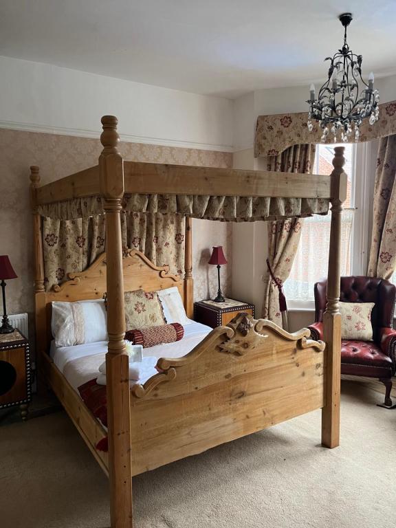 洛斯托夫特月桂树别墅酒店的一间卧室配有一张天蓬床和一把椅子