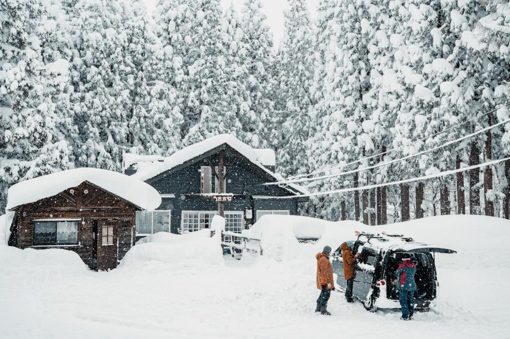 妙高Mountain Hut Myoko的一群人站在小屋前的雪中