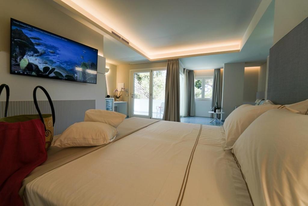 梵蒂冈角伊登村公寓式酒店的一间卧室设有两张床,墙上配有电视。