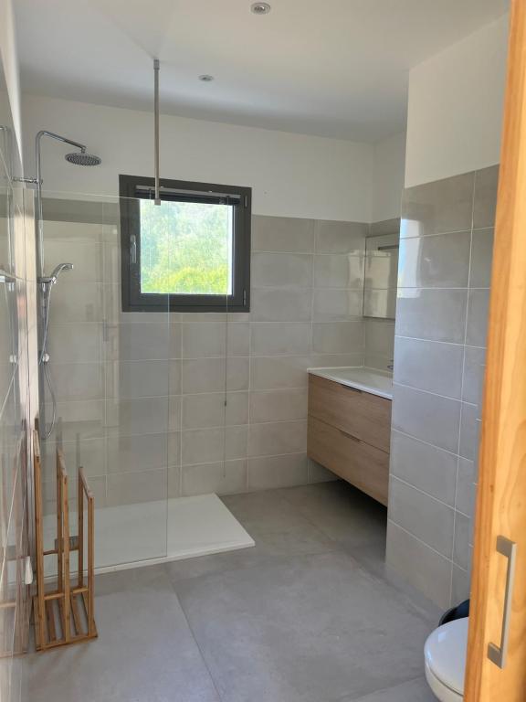 卡尔热斯Villa Cargese的带淋浴和盥洗盆的浴室以及窗户。