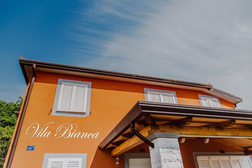 乌马格Vila Bianca的一座橙色的建筑,上面有白色百叶窗