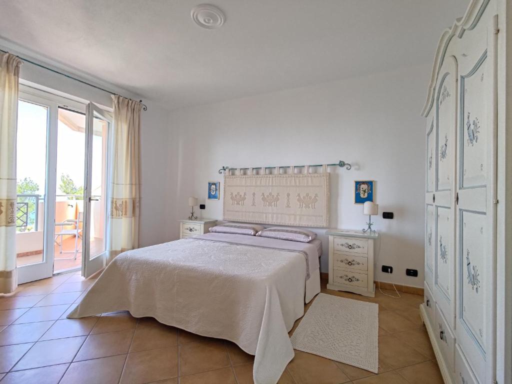 内比达Splendida vista sul mare的白色的卧室设有床和大窗户
