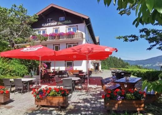 默尼希基兴Alpengasthof Fernblick的大楼前的餐厅,配有桌子和遮阳伞