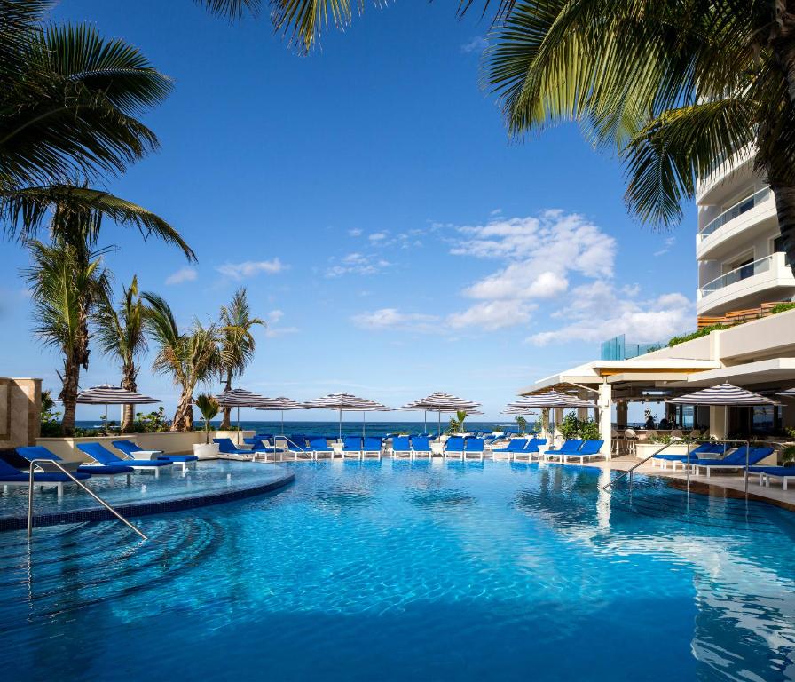 圣胡安康达多范德比尔特酒店的一个带蓝色椅子的游泳池,棕榈树