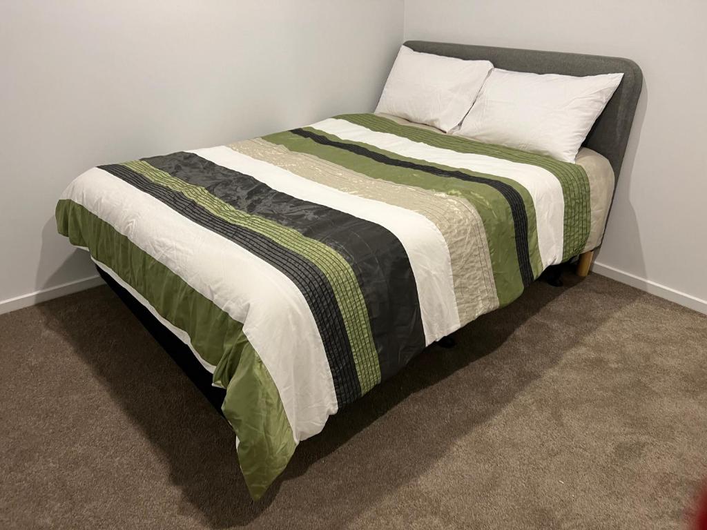 克兰伯恩Ann pavilion Paradise的床上铺有绿色和白色的毯子