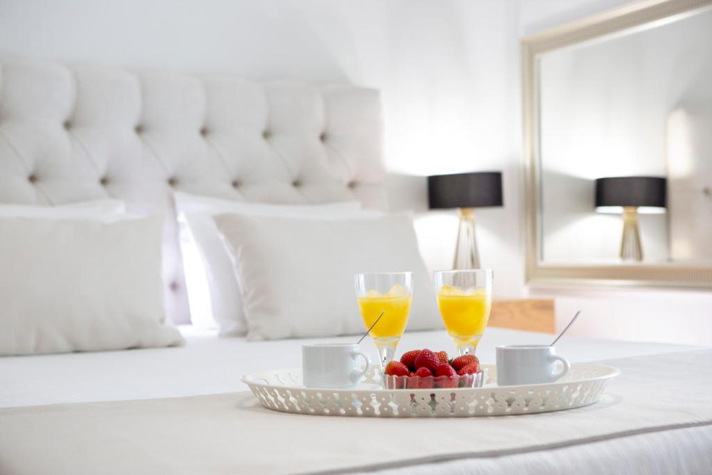 奈德里Adria Luxury Apartments的床上的托盘,上面放有两杯橙汁和水果