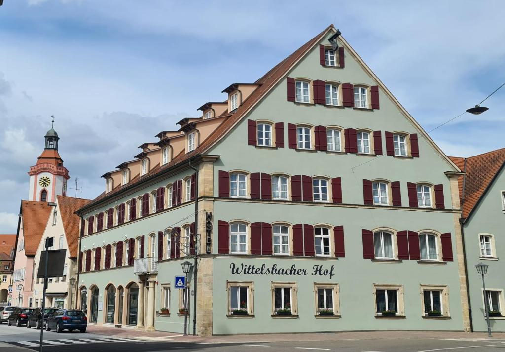 拜恩州魏森堡Wittelsbacher Hof Weißenburg的一座白色的大建筑,设有红色的窗户和钟楼