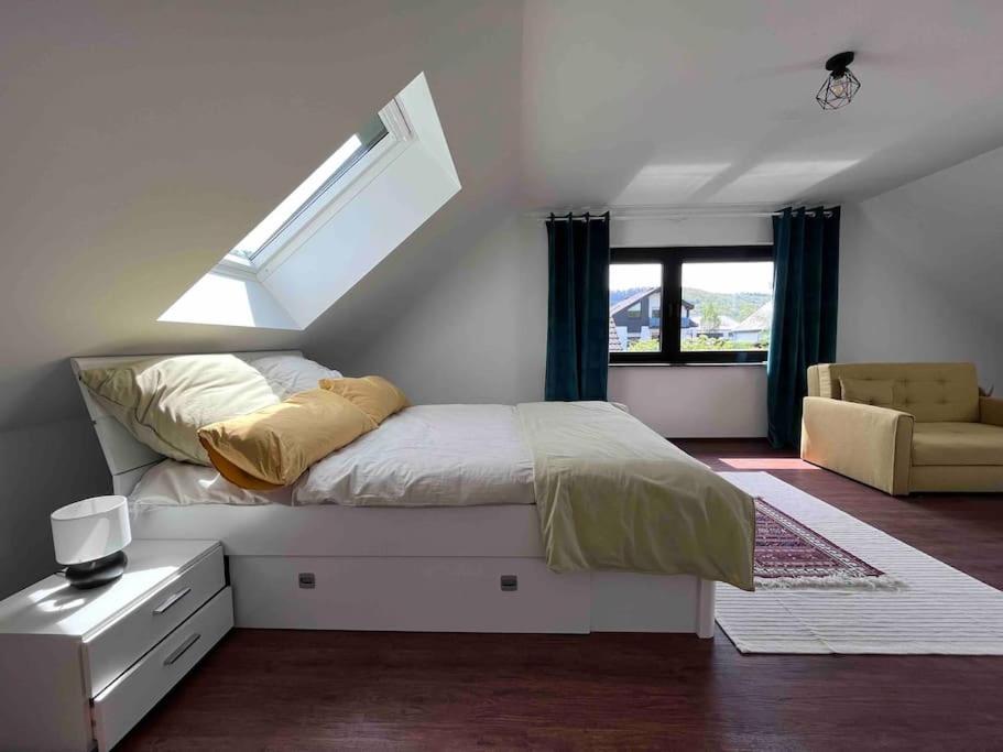 格罗尔斯泰因Gasthaus Maarfeld Gerolstein的白色卧室配有带窗户和椅子的床