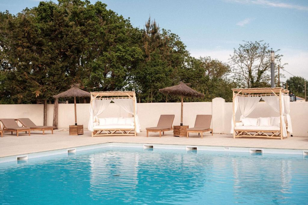 马雷讷INSPIRE Villages - Marennes Oléron的游泳池旁的游泳池配有椅子和遮阳伞