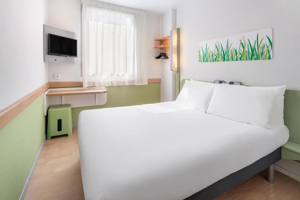 萨拉戈萨B&B HOTEL Zaragoza Plaza Mozart的卧室配有白色的床和电视