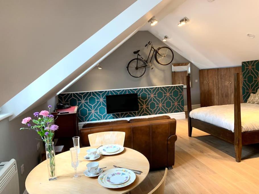 剑桥Scholar's Loft - Cosy & Close to Central Cambridge的客厅配有桌子,墙上挂有自行车