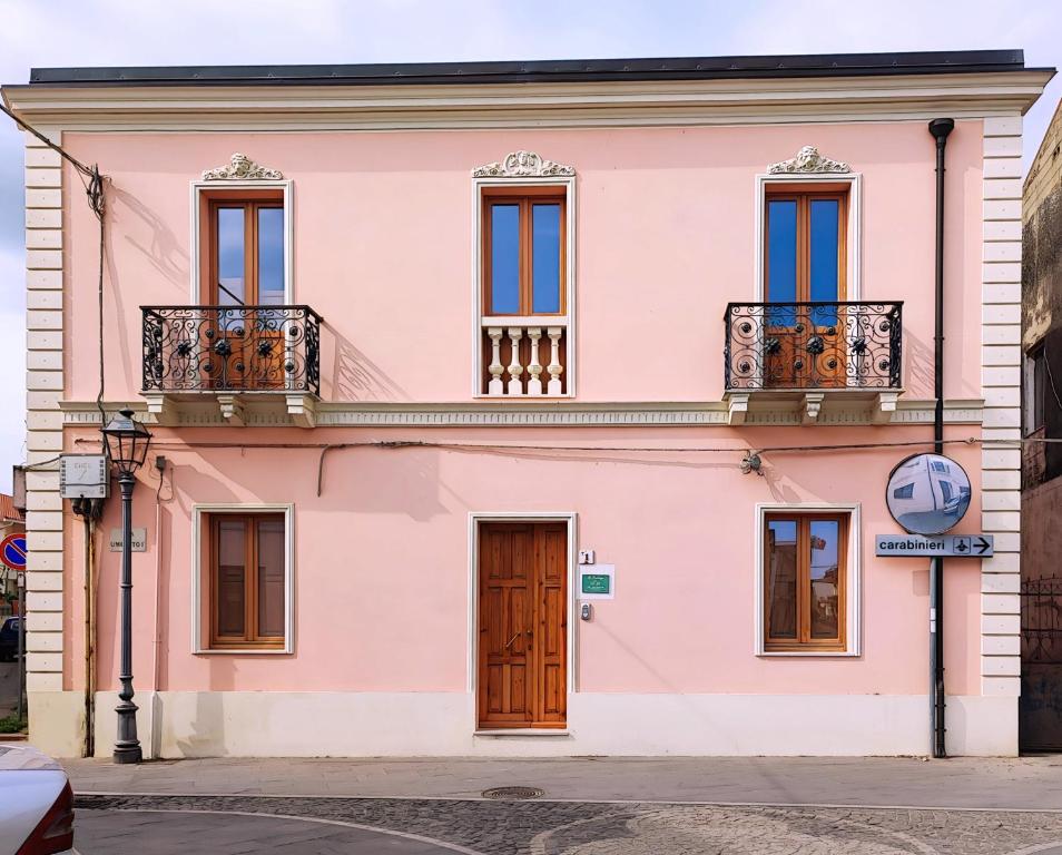GibaLa Residenza B&B的粉红色的建筑,设有窗户和阳台,位于街道上