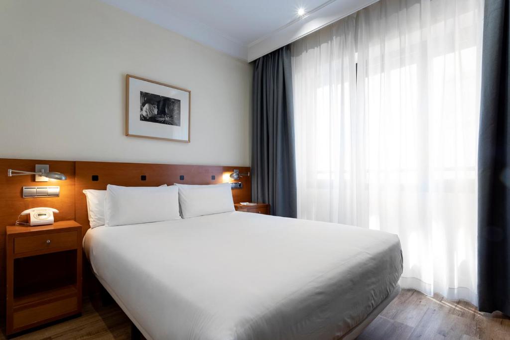马德里珀蒂宫赛珀格兰维尔酒店的卧室设有一张白色大床和一扇窗户。