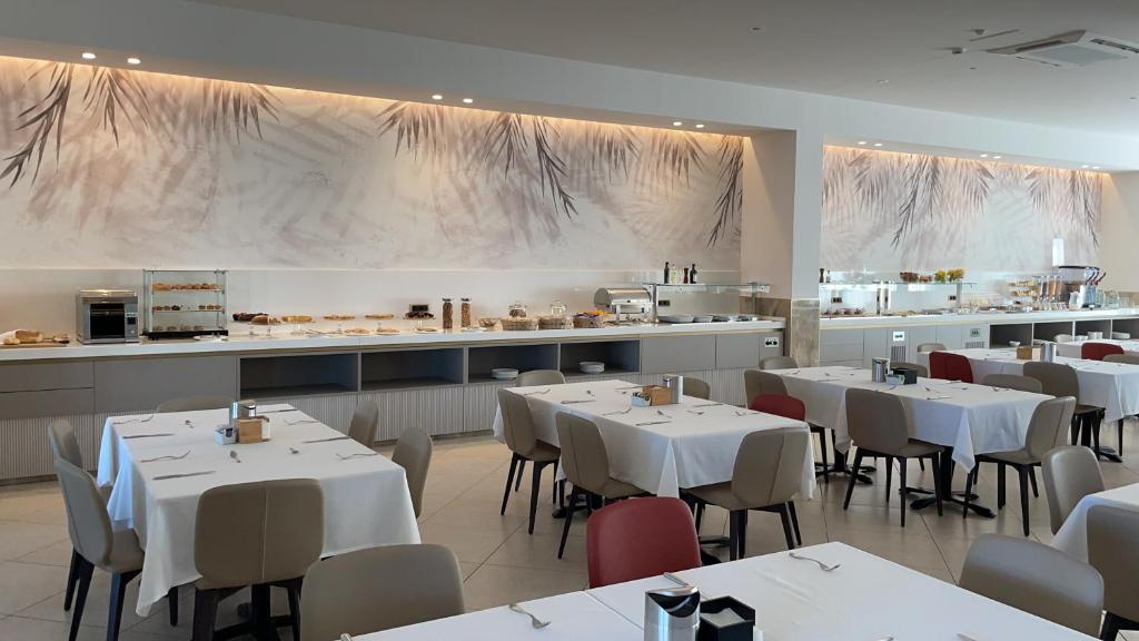 切萨雷奥港Onda B&B的一间带白色桌椅的餐厅和一间厨房