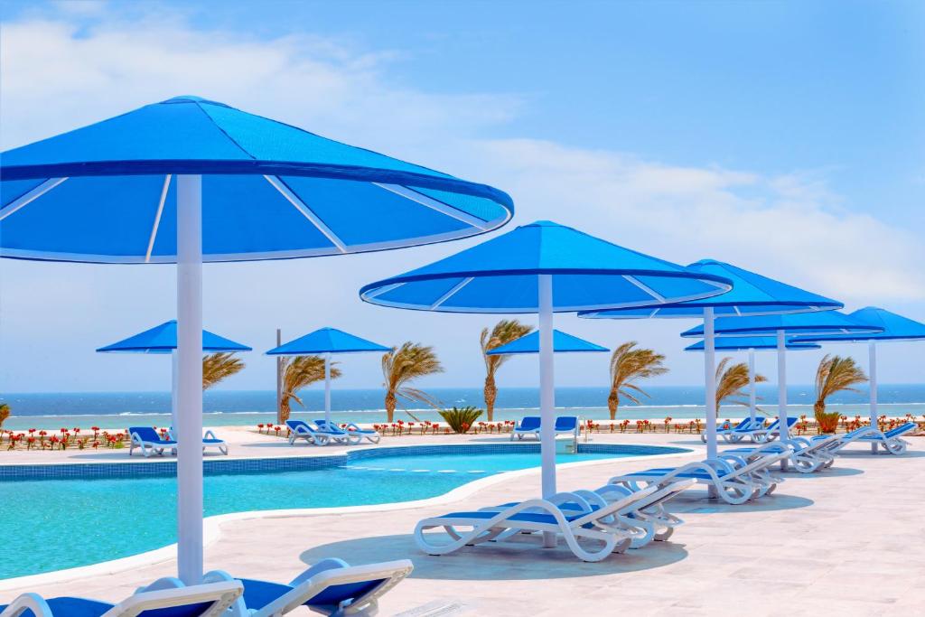 马萨阿拉姆Pickalbatros Villaggio Aqua Park - Portofino Marsa Alam的一组蓝色遮阳伞和椅子,位于游泳池旁
