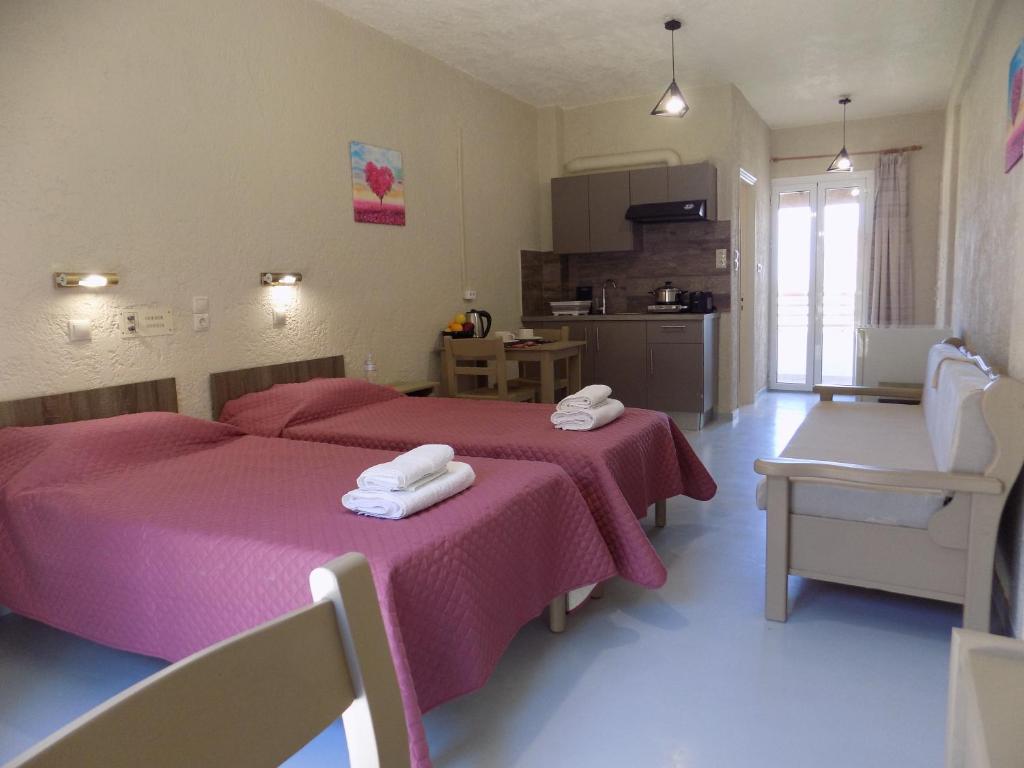 阿依亚埃夫菲亚Afrodite Spacious Apartments!的一间卧室配有两张带粉色床单的床,还设有一间厨房