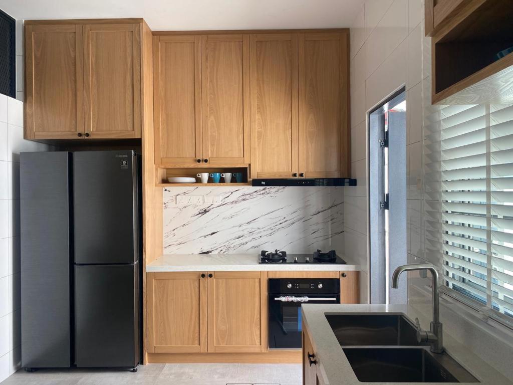 加影Timurahaus的厨房配有木制橱柜和黑色冰箱。