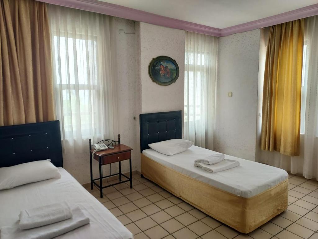 阿拉尼亚Kleopatra Sahara Hotel的一间卧室设有两张床、一张桌子和窗户。