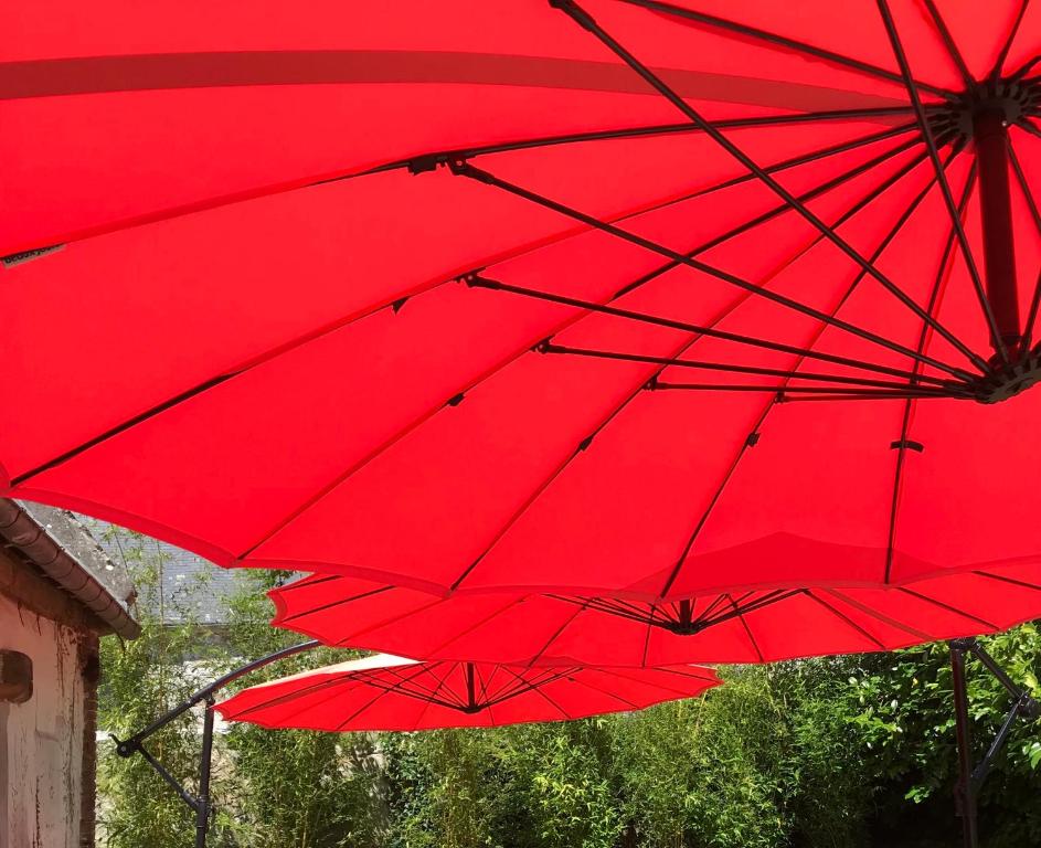 Gueutteville-les-GrèsROUGE COTTAGE Gîte 4 étoiles Billard的一组红色伞,坐在大楼旁边