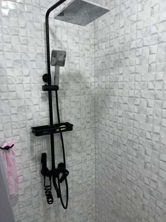 GarniGuest House SAMAN的白色瓷砖浴室内带电话的淋浴