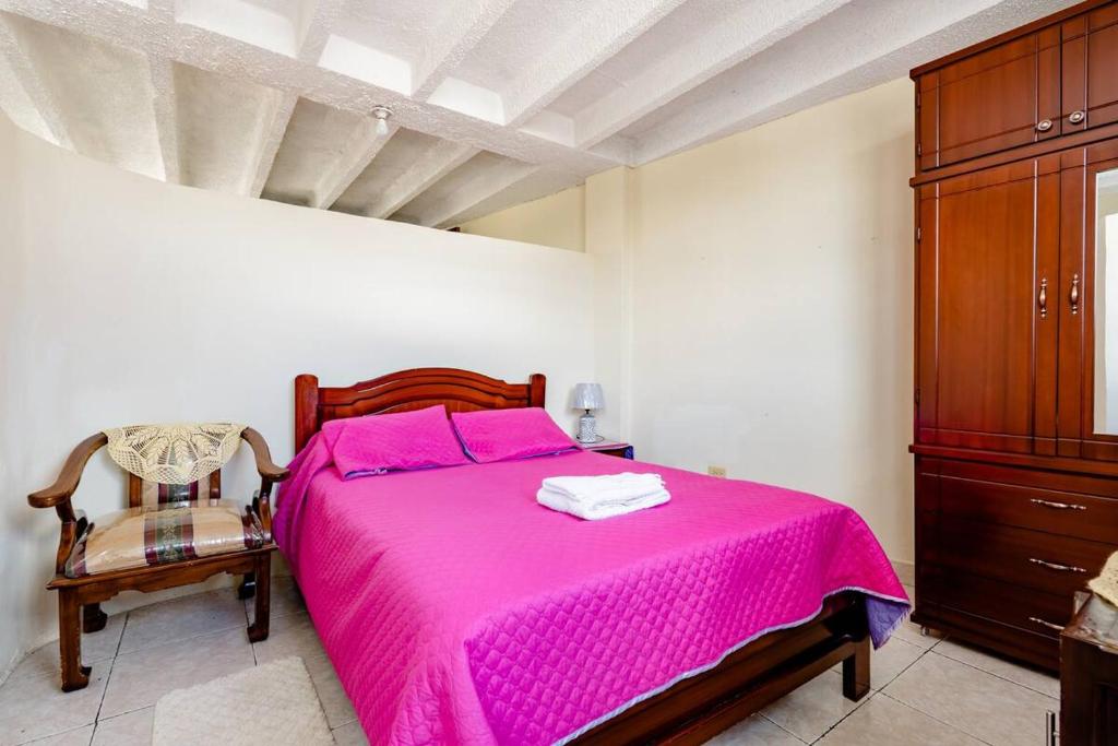 基多SUITE AMOBLADA TODO INCLUIDO的卧室配有粉红色的床和椅子