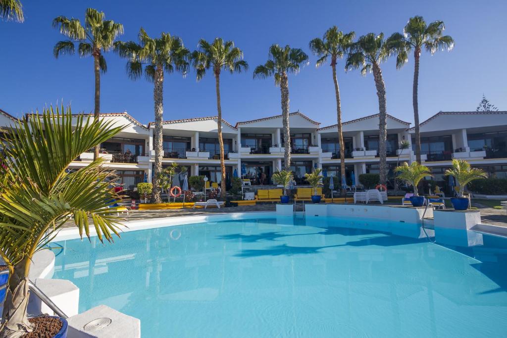 圣阿古斯丁Sunsuites Carolina & Collection的酒店前方的棕榈树游泳池