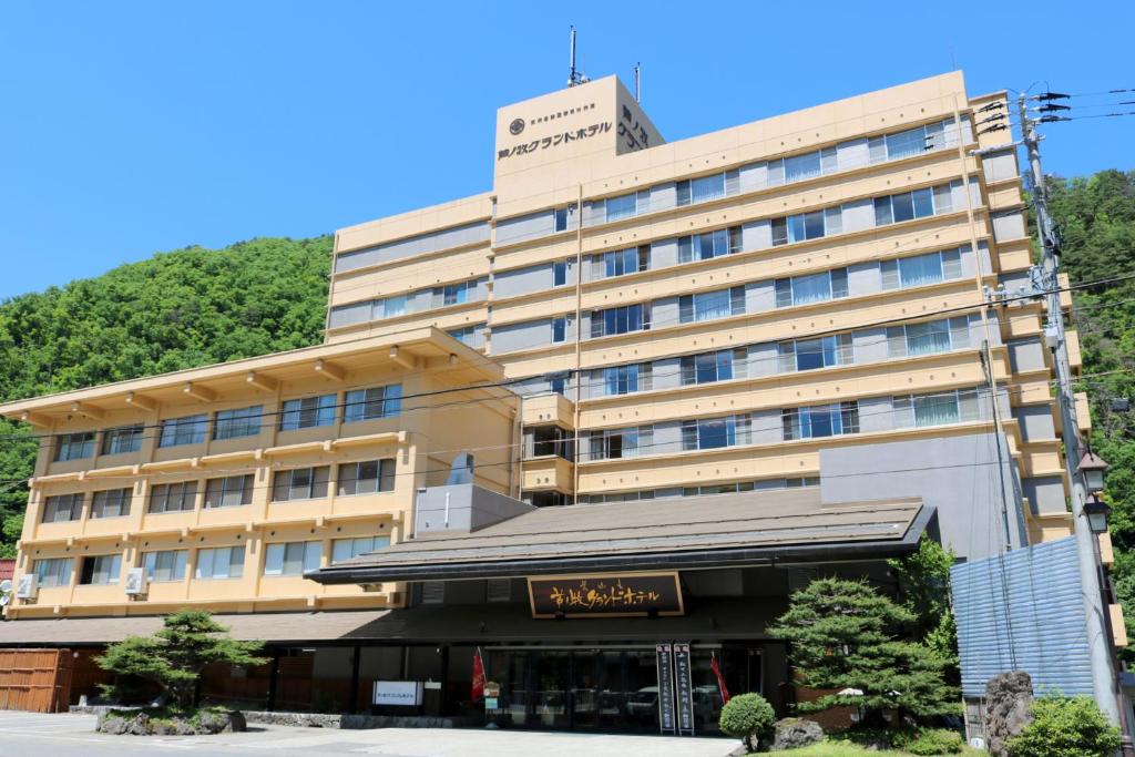 会津若松Ashinomaki Grand Hotel的一座大建筑,背景是一座山